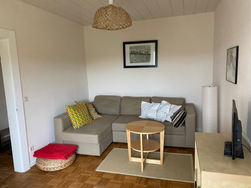 Gemütliches Wohnzimmer mit Sofa, Tisch, Fernseher und heller Dekoration.